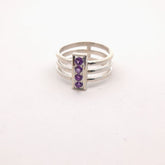 Silver ring with purple gemstones on a white background