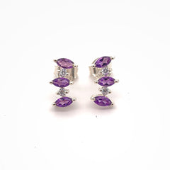 Pair of silver earrings with purple gemstones on a white background