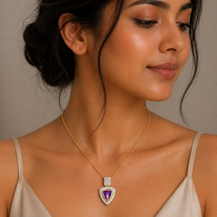 Woman wearing a gold necklace with a purple heart-shaped pendant against a neutral background