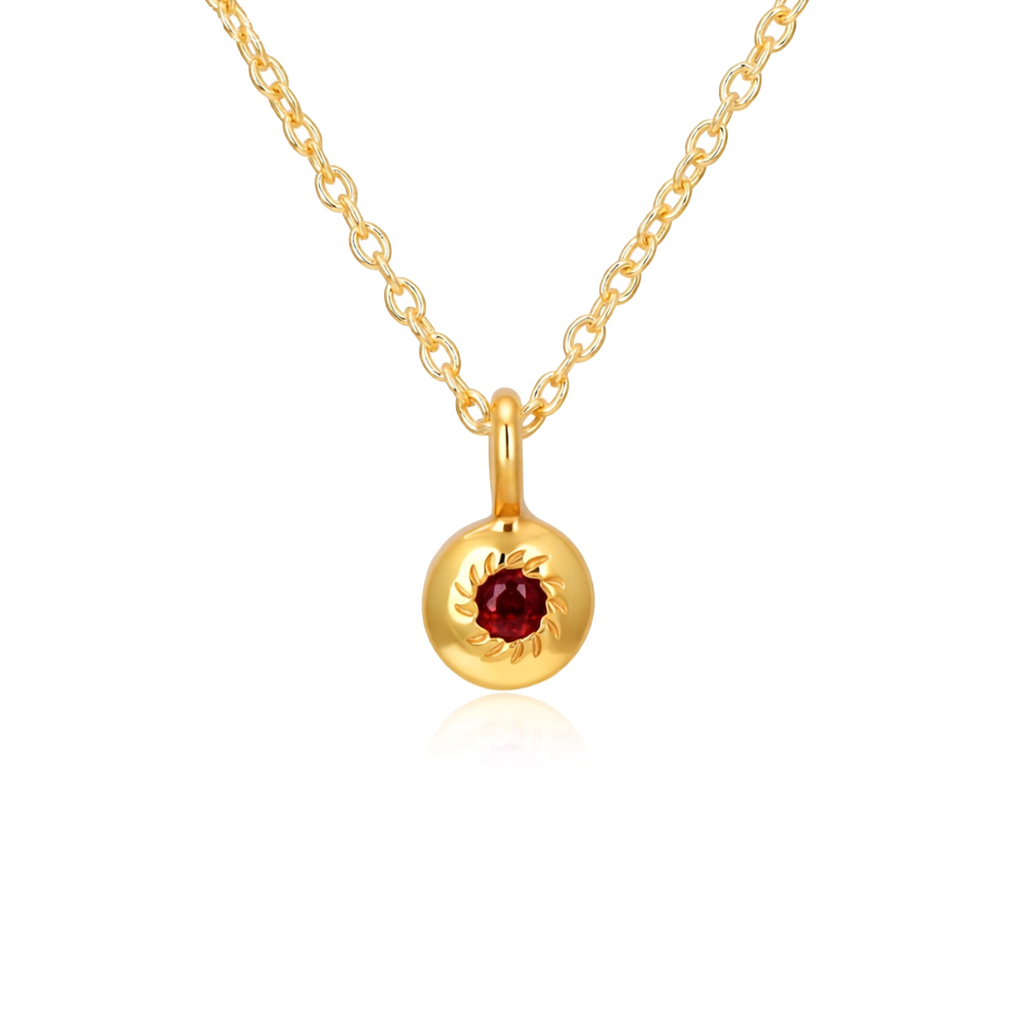 Gold necklace with a round pendant featuring a red gemstone on a white background