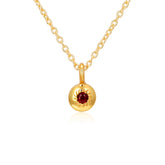 Gold necklace with a round pendant featuring a red gemstone on a white background