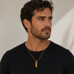 Man wearing a black shirt and gold necklace against a neutral background