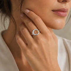 Woman wearing a silver ring, touching her neck against a neutral background
