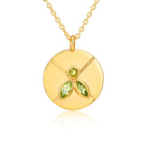 Gold necklace with a circular pendant featuring green gemstones on a white background
