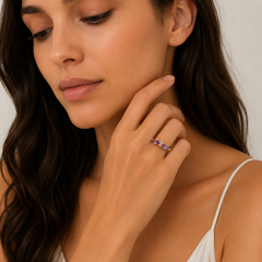Woman wearing a ring with purple gemstones, close-up of face and hand.