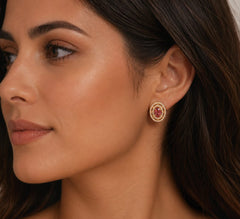 Close-up of a woman wearing a gold earring with a red gemstone.