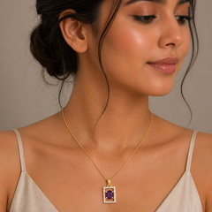 Woman wearing a gold necklace with a purple gemstone pendant against a neutral background