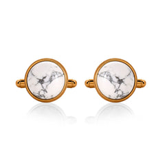 Pair of cufflinks with gold frames and white marbled centers on a white background