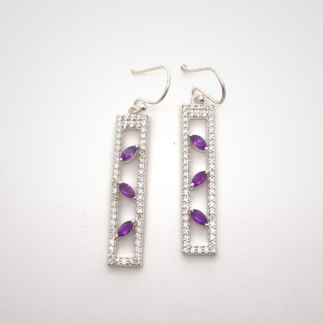 Silver earrings with purple gemstones on a white background