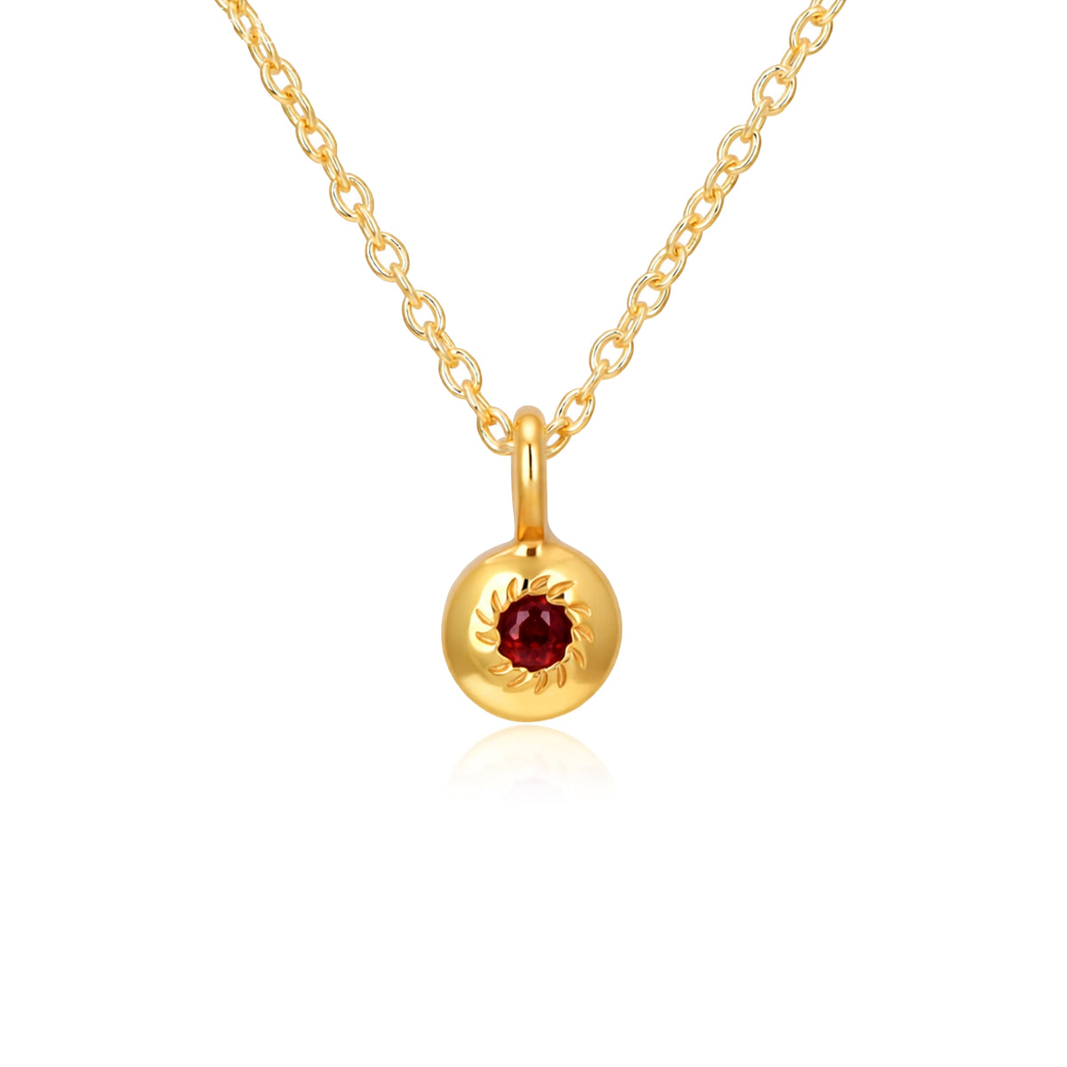Gold necklace with a round pendant featuring a red gemstone on a white background