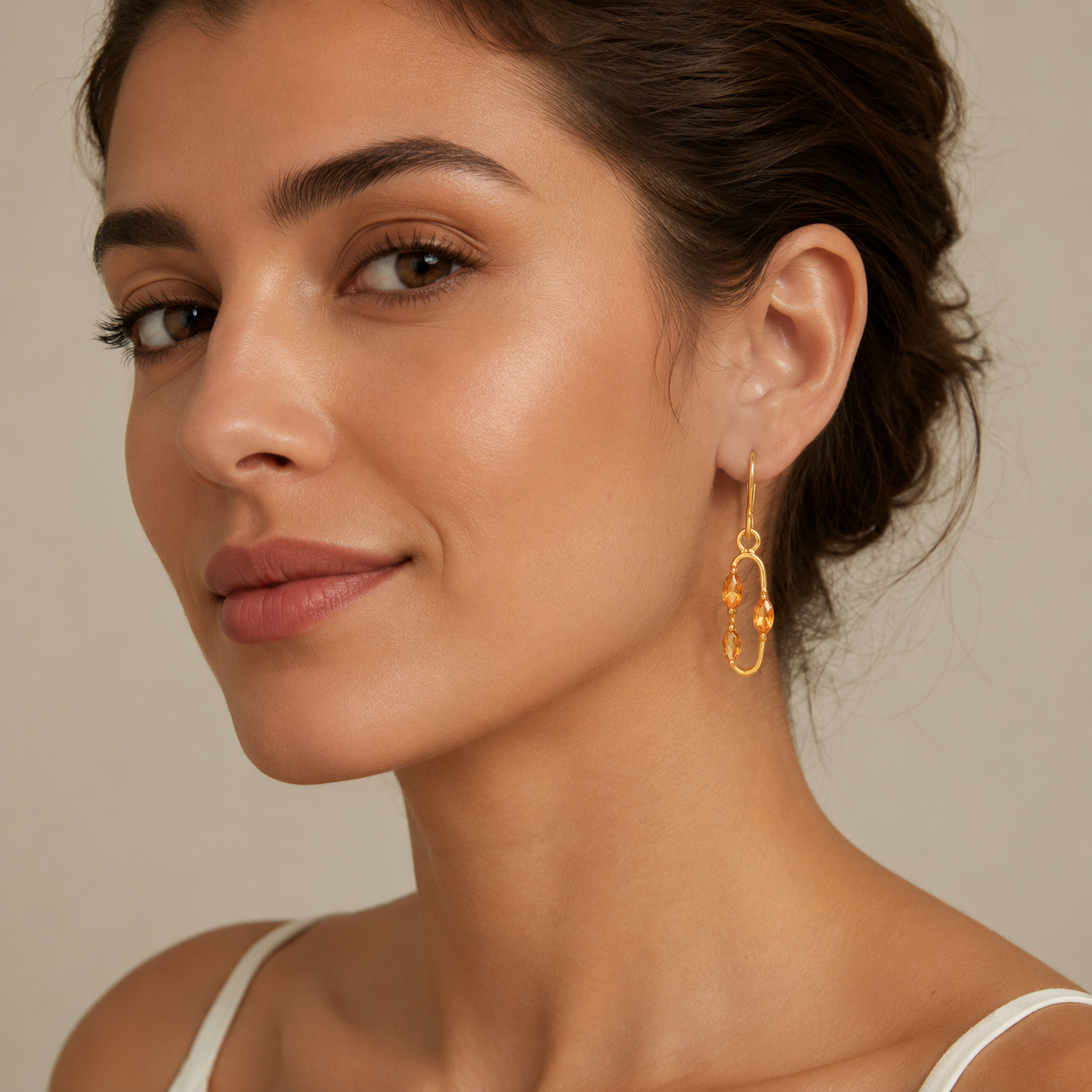 Close-up of a woman wearing gold hoop earrings against a neutral background