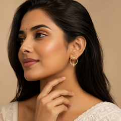 Woman wearing gold hoop earrings with a beige background