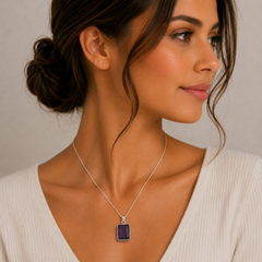 Woman wearing a necklace with a purple pendant against a neutral background