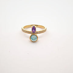 Gold ring with purple and green gemstones on a white background
