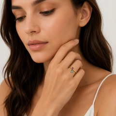 Woman wearing a gold ring with multicolored gemstones on a neutral background