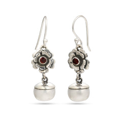 Silver earrings with floral designs and red gemstones on a white background