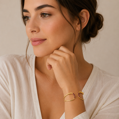 Woman wearing a gold bracelet with a neutral background