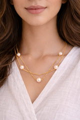 Close-up of a woman wearing a gold necklace with pearls.
