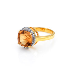 Gold ring with a large orange gemstone and smaller diamonds on a white background