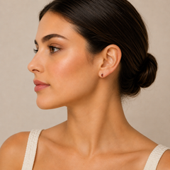 Woman wearing a small earring against a neutral background