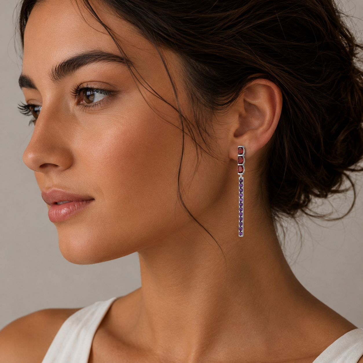 Close-up of a woman wearing colorful earrings against a neutral background