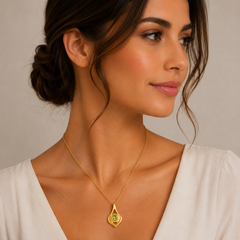 Woman wearing a gold necklace with a green pendant against a neutral background