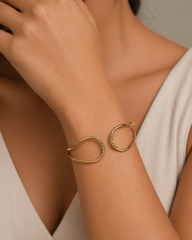 Gold bracelet with green gemstones on a person's wrist against a neutral background
