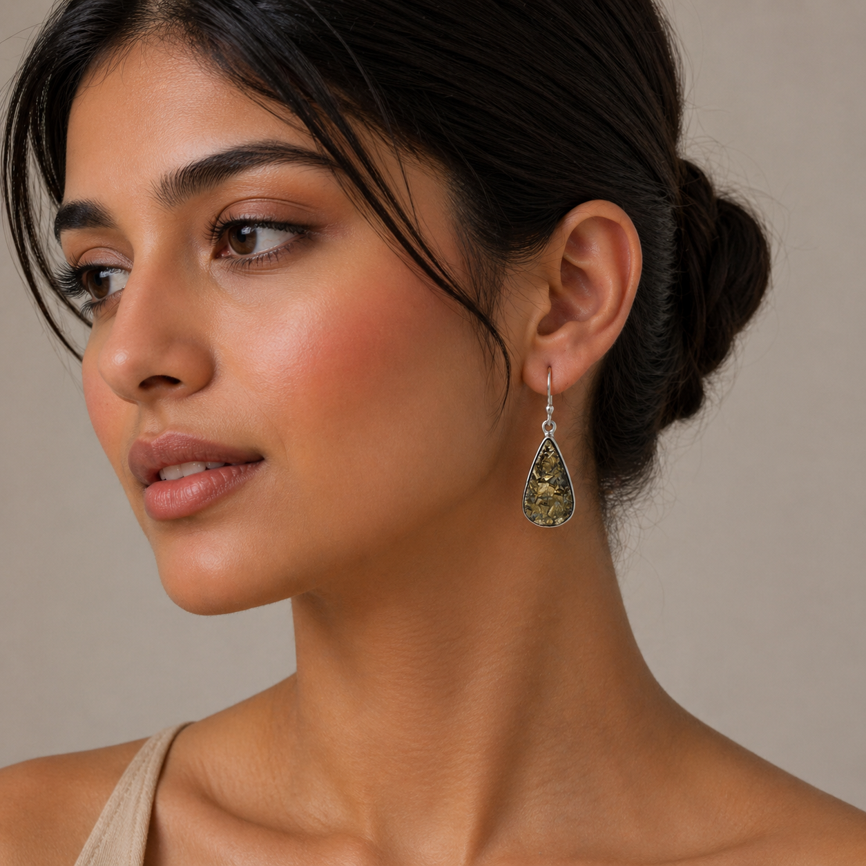 Woman wearing a teardrop-shaped earring with a beige background