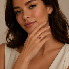 Woman wearing a ring with a red gemstone against a neutral background