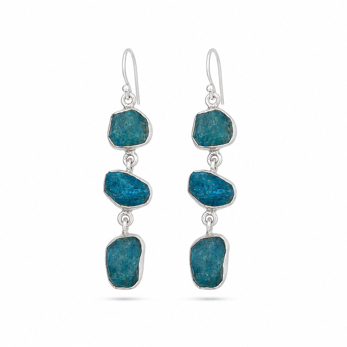 A pair of silver drop earrings featuring three raw, irregular blue- stones in each earring, suspended from silver fishhook wires, shown against a plain white background.