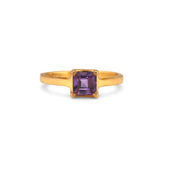 Gold ring with a purple gemstone on a white background