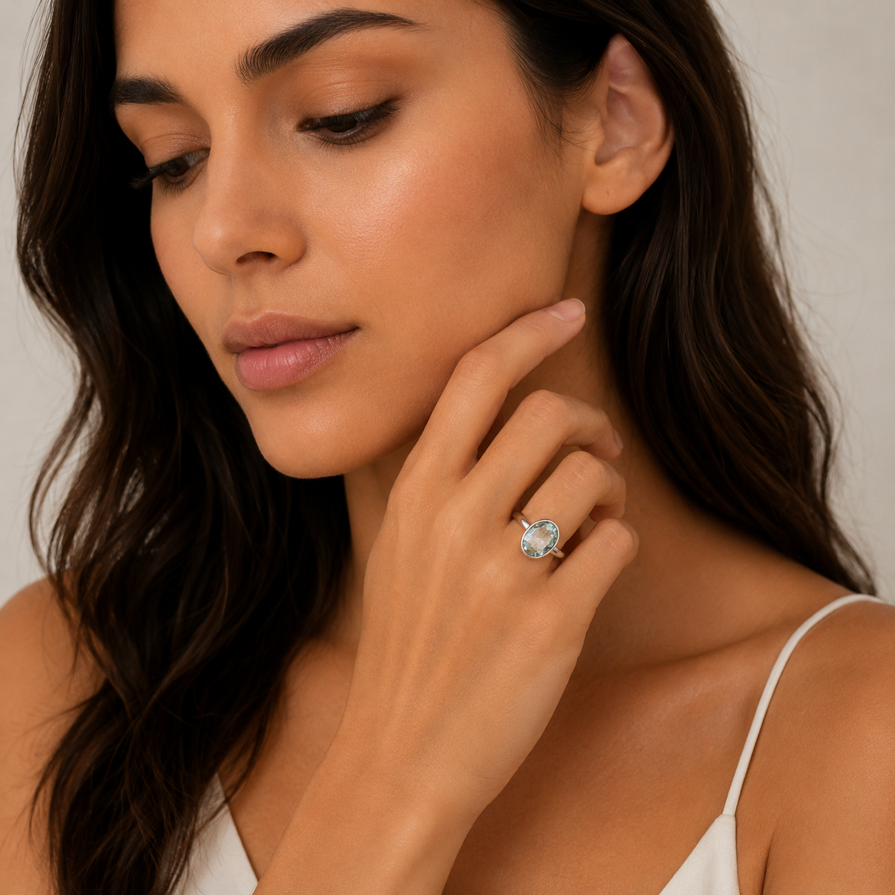 Woman wearing a ring with a clear gemstone on a neutral background