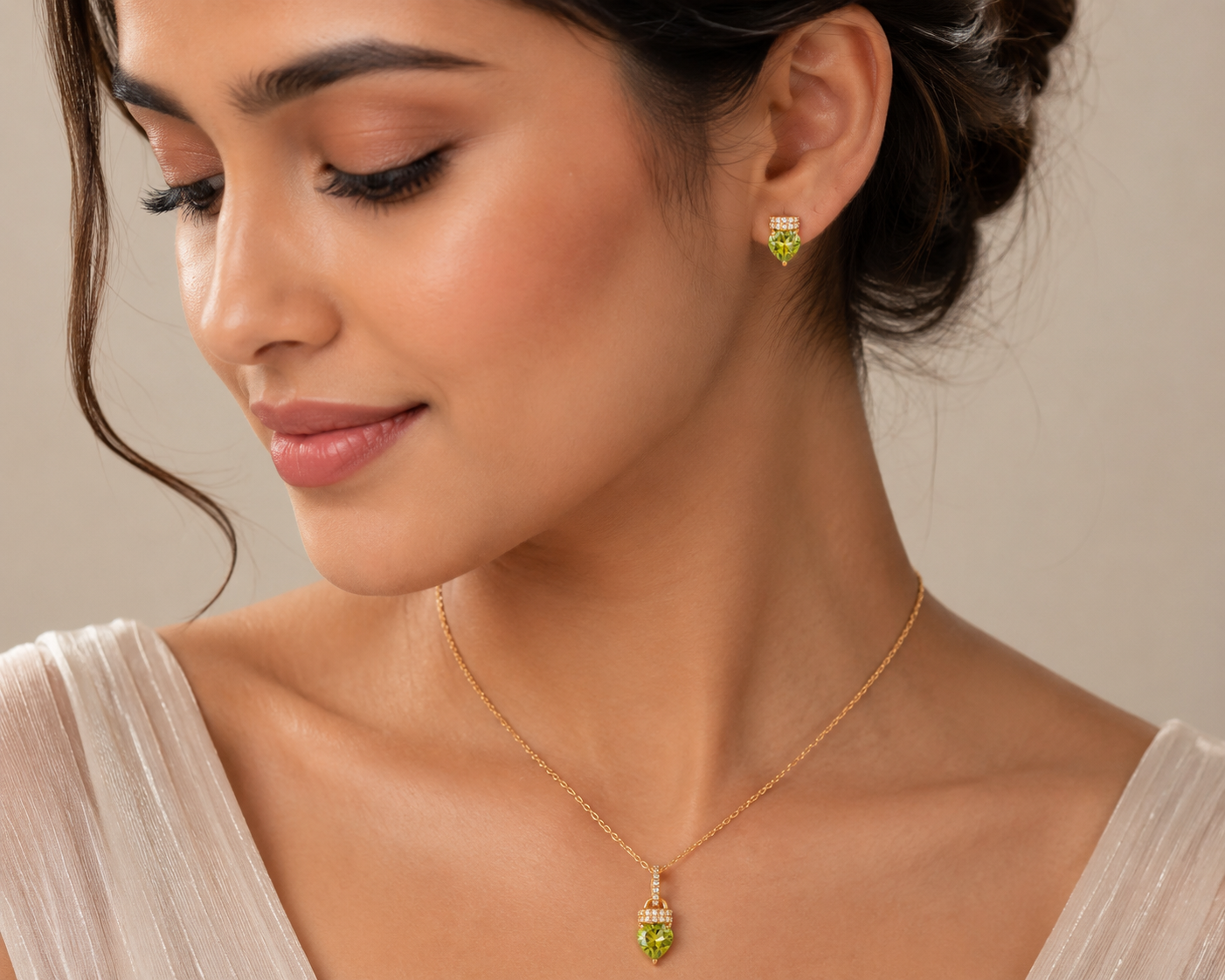 Woman wearing a gold necklace and green earrings against a neutral background