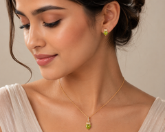 Woman wearing a gold necklace and green earrings against a neutral background
